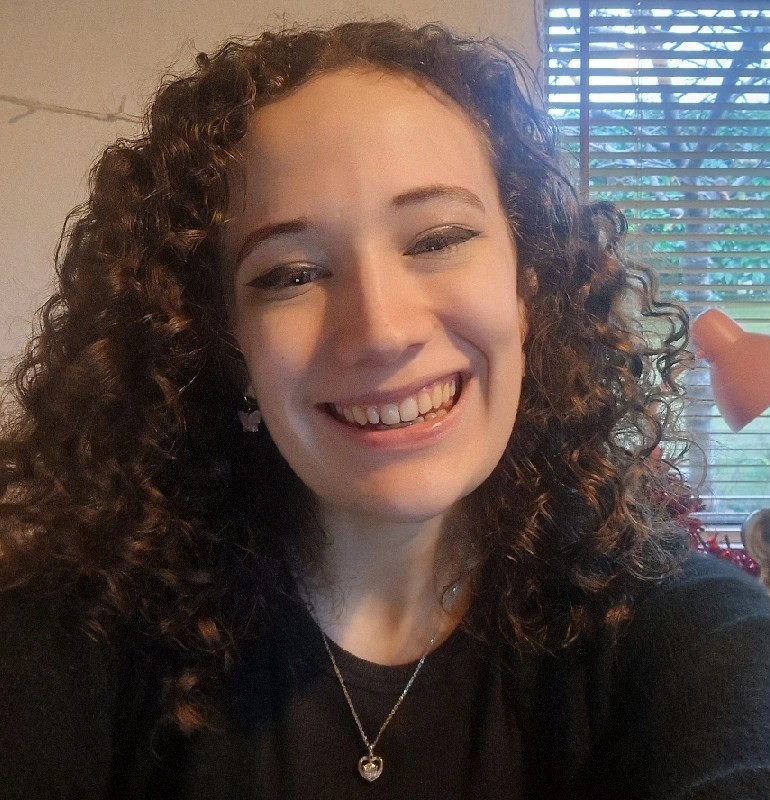 A picture of Zoe Cox. She is in a black cardigan, and has white skin and has brown curly hair.
